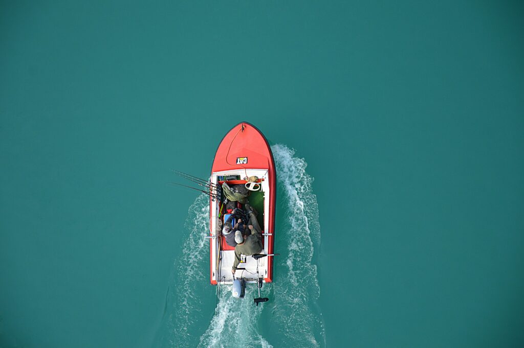 pexels-photo-240561-240561 Top view of a red motorboat with fishermen navigating open turquoise waters.